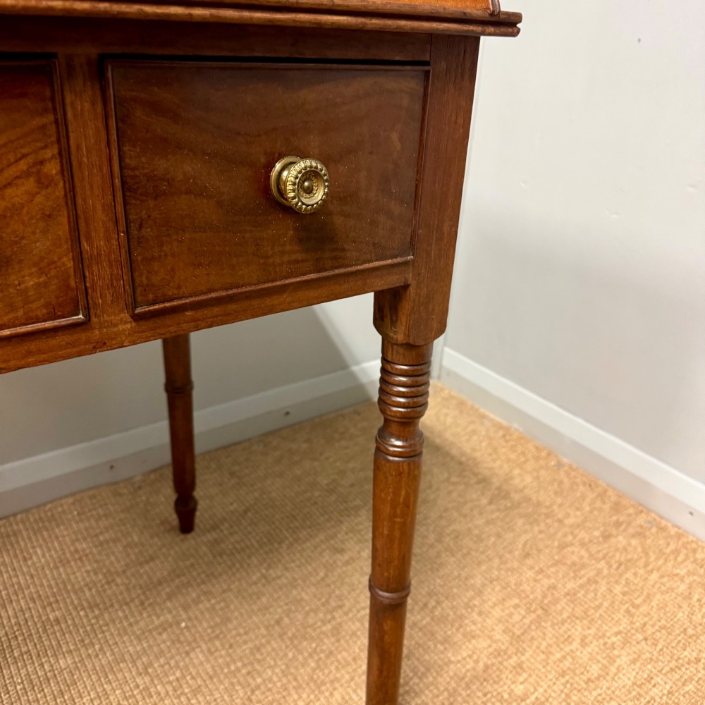 A Regency mahogany dressing table featuring three drawers with round brass knobs, a raised gallery top, and four turned tapered legs. View VII
