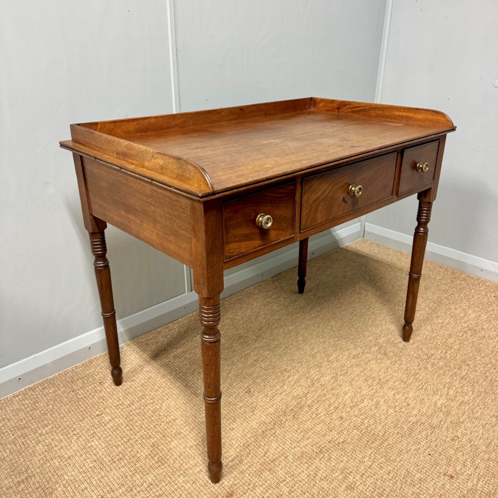 A Regency mahogany dressing table featuring three drawers with round brass knobs, a raised gallery top, and four turned tapered legs. View VIII