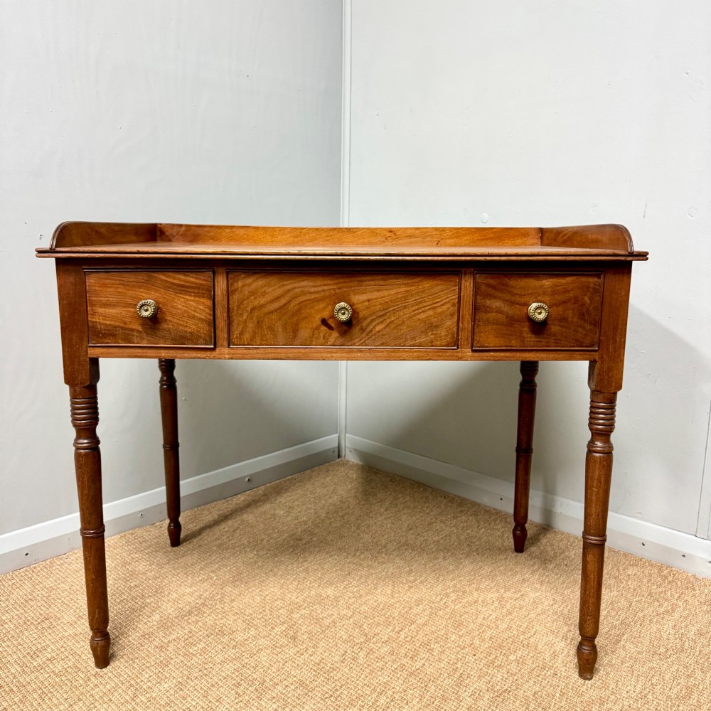 A Regency mahogany dressing table featuring three drawers with round brass knobs, a raised gallery top, and four turned tapered legs. View IX