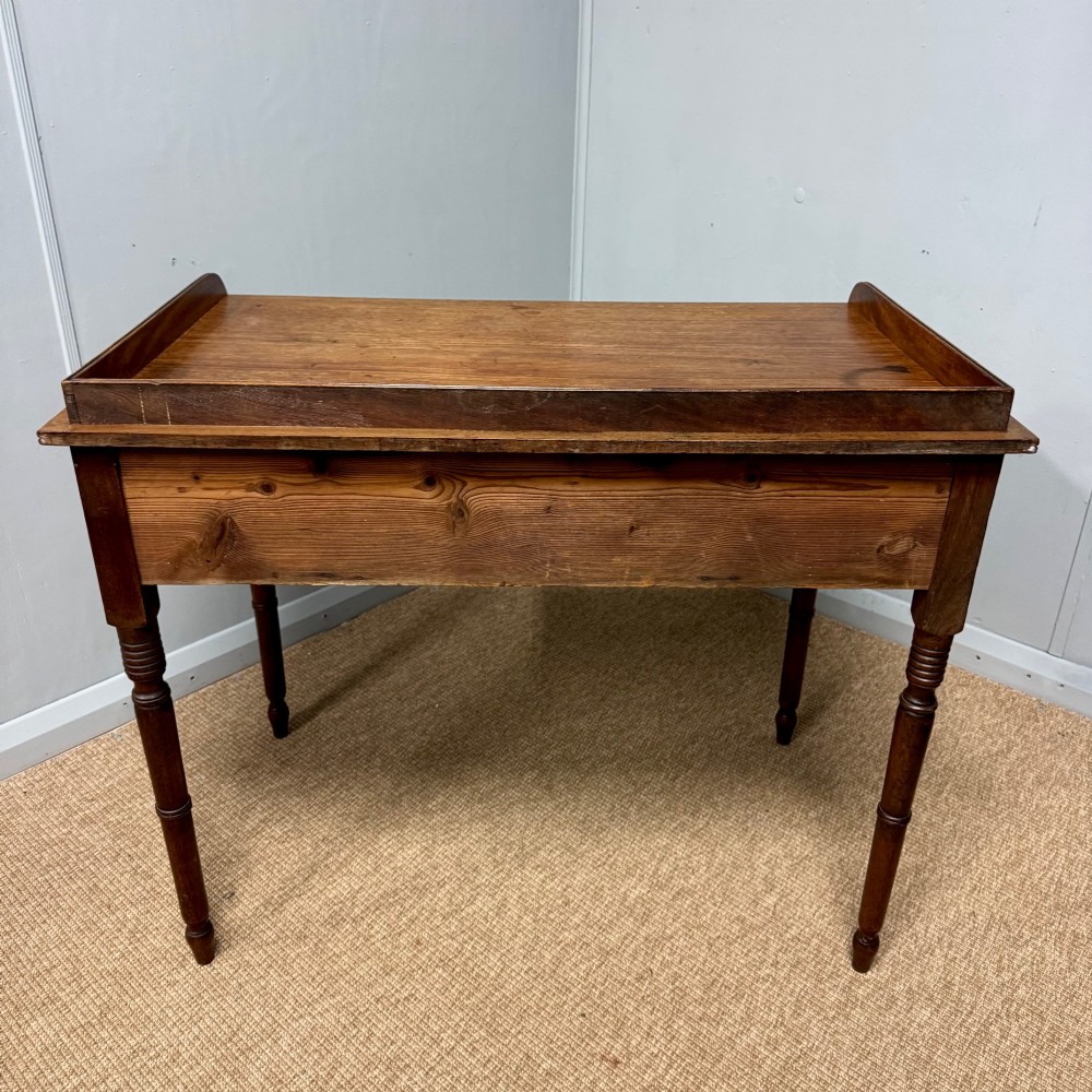 A Regency mahogany dressing table featuring three drawers with round brass knobs, a raised gallery top, and four turned tapered legs. View X