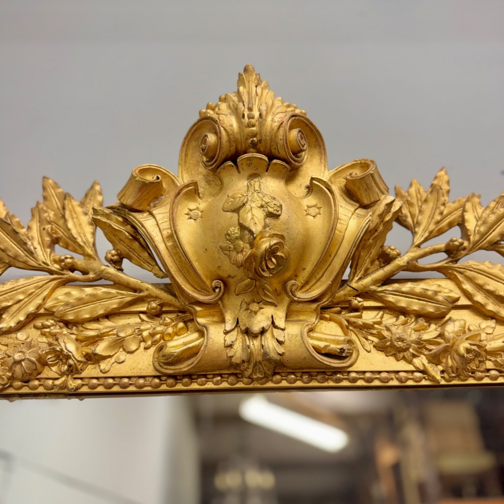 A large rectangular French Louis XVI style water gilded mirror featuring fluted side pilasters and an elaborate carved crest with laurel leaves and urn finials. View III
