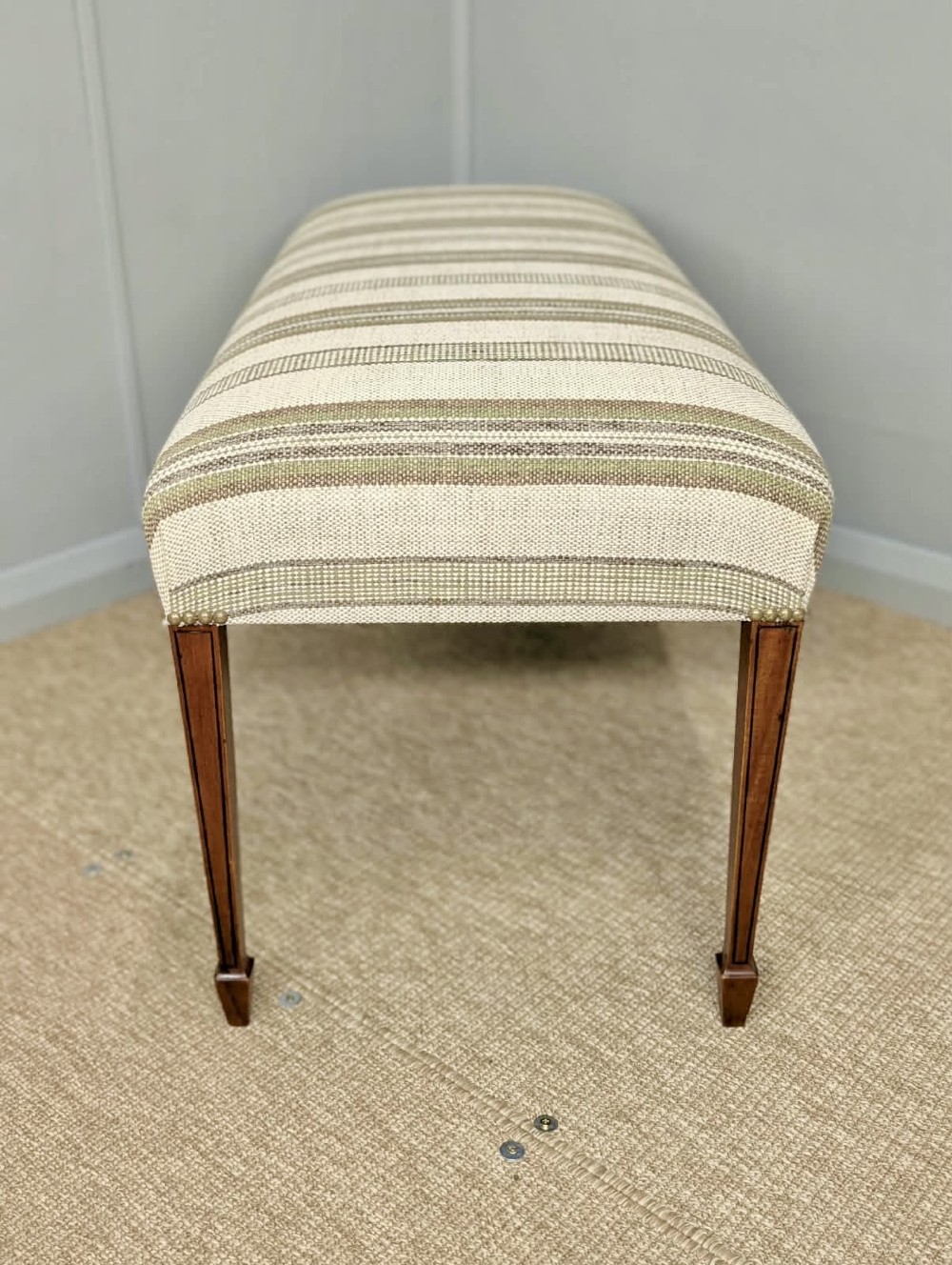 An Edwardian rectangular satinwood piano stool upholstered in beige striped fabric with square tapered legs. View V