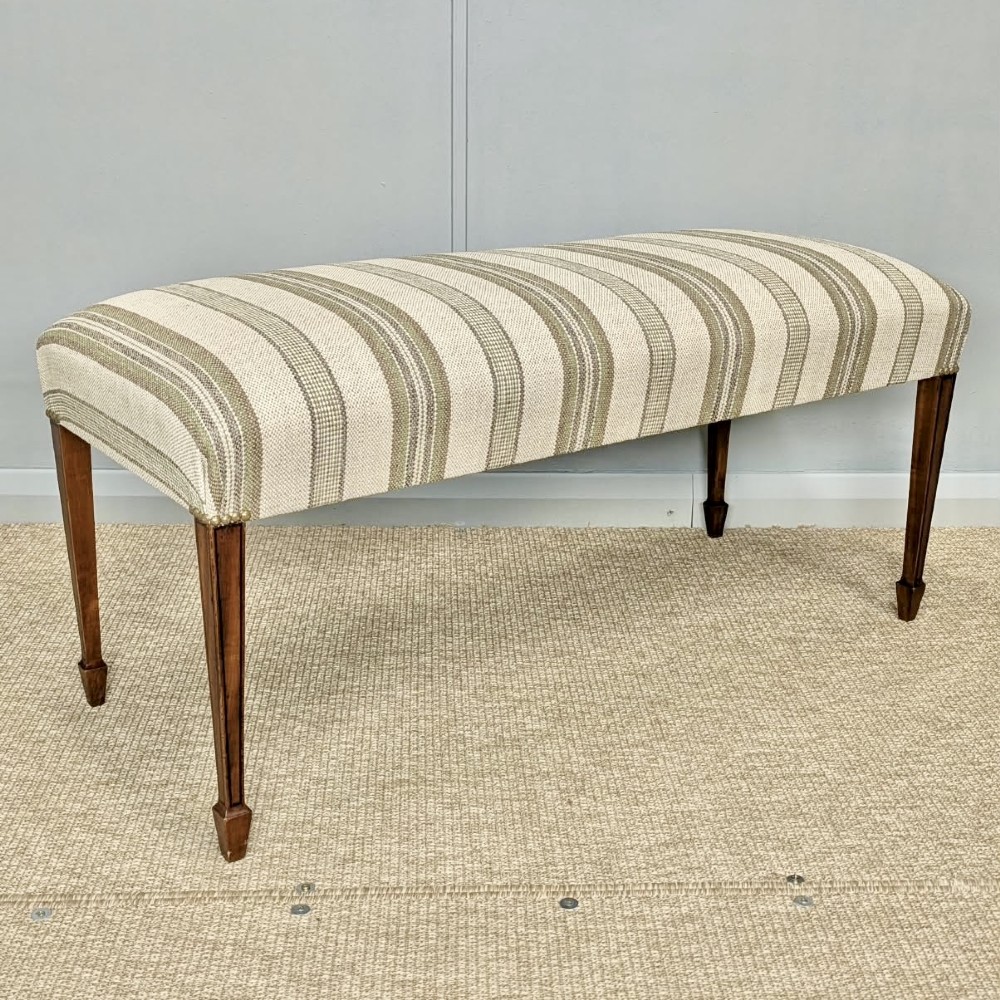 An Edwardian rectangular satinwood piano stool upholstered in beige striped fabric with square tapered legs. View VIII