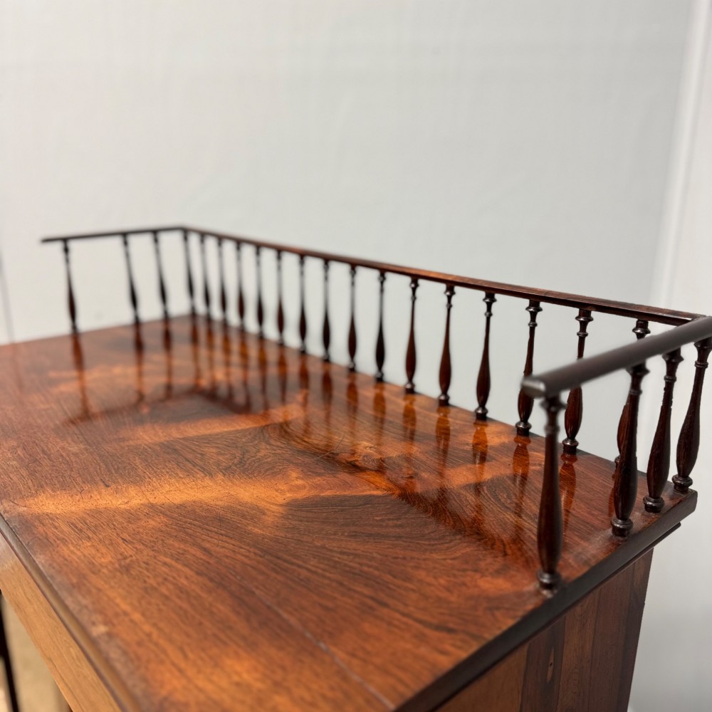 A dark brown Regency rosewood pier cabinet featuring a spindle gallery top, plain apron, and twin glazed doors resting on a plinth base. View VI