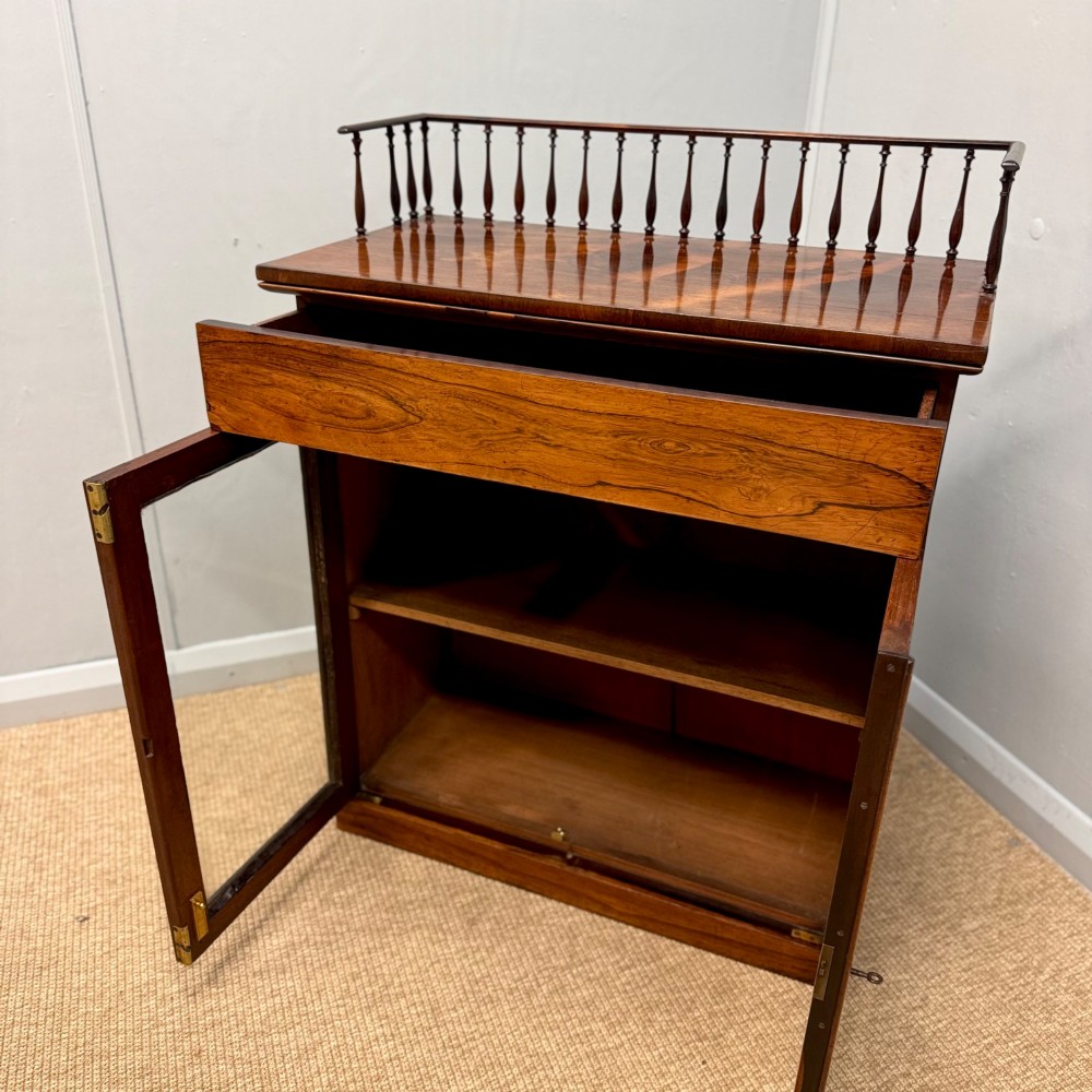 A dark brown Regency rosewood pier cabinet featuring a spindle gallery top, plain apron, and twin glazed doors resting on a plinth base. View VII