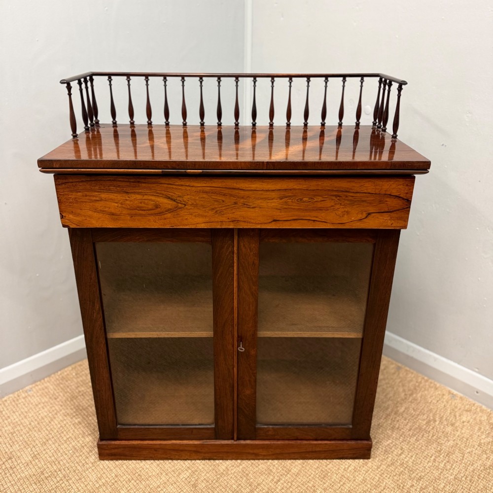 A dark brown Regency rosewood pier cabinet featuring a spindle gallery top, plain apron, and twin glazed doors resting on a plinth base. View VIII