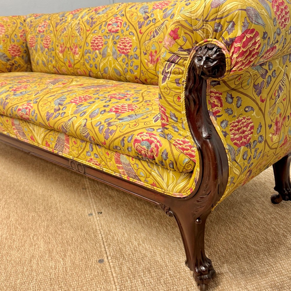 A Late Regency mahogany sofa featuring scroll arms, carved lion mask details, and yellow botanical William Morris style upholstery. View II