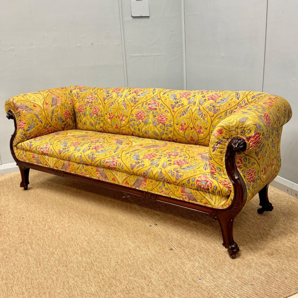 A Late Regency mahogany sofa featuring scroll arms, carved lion mask details, and yellow botanical William Morris style upholstery. View IV