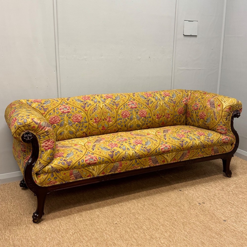 A Late Regency mahogany sofa featuring scroll arms, carved lion mask details, and yellow botanical William Morris style upholstery. View VI