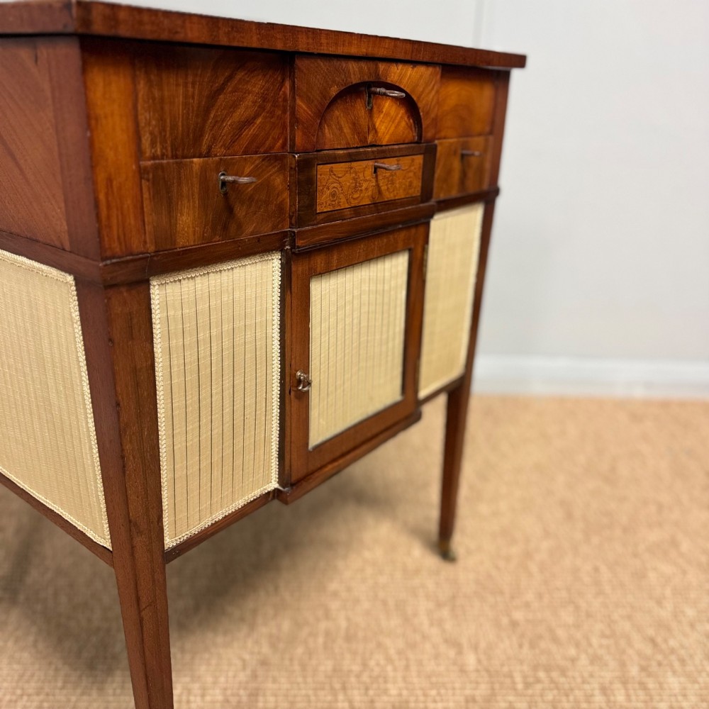 A late Georgian mahogany work table with an open hinged lid revealing fitted interior compartments, pleated fabric side panels, and square tapered legs on brass castors. View VIII