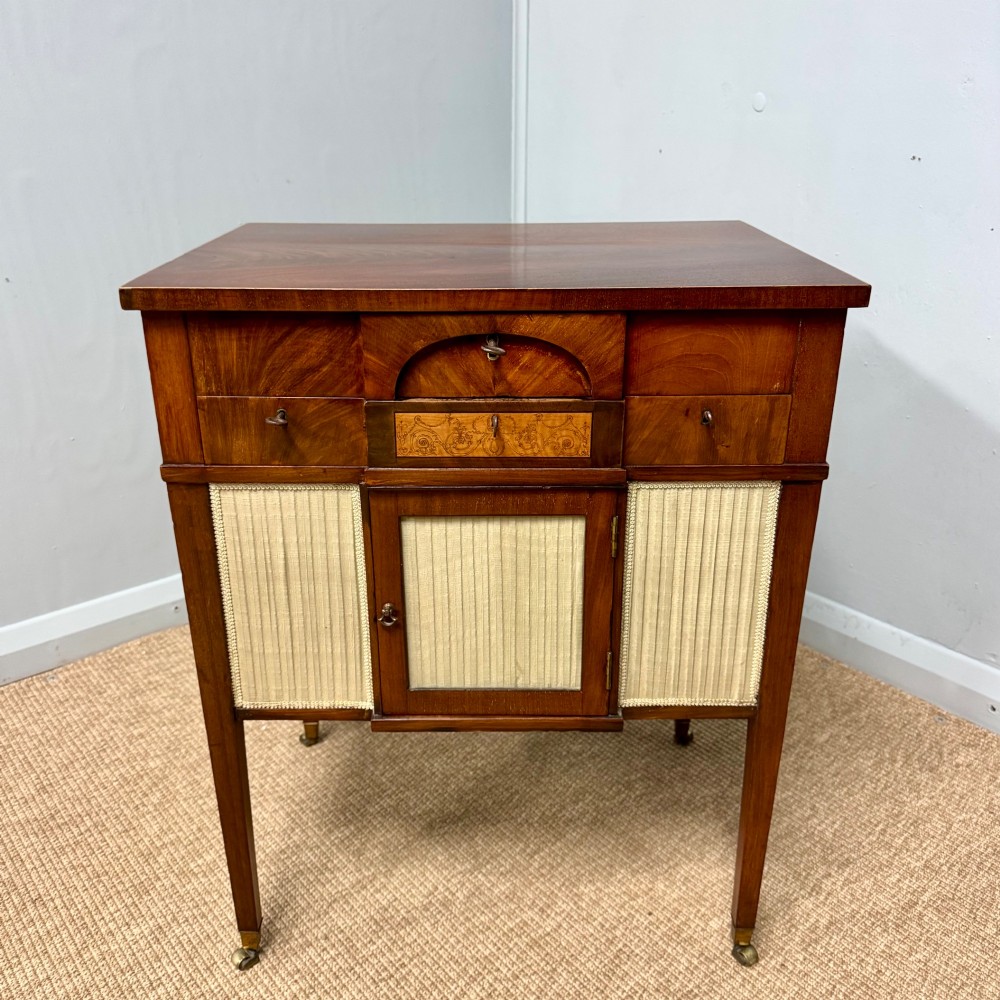 A late Georgian mahogany work table with an open hinged lid revealing fitted interior compartments, pleated fabric side panels, and square tapered legs on brass castors. View IX