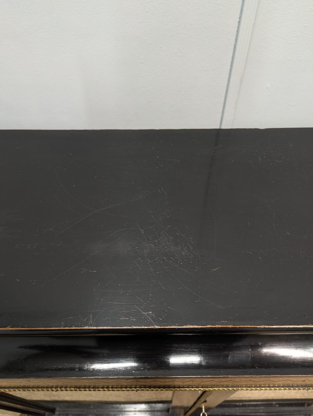 A black ebonised two-door glazed cabinet featuring a moulded caddy top, brass ormolu corner mounts, and a band of geometric marquetry inlay. View IX
