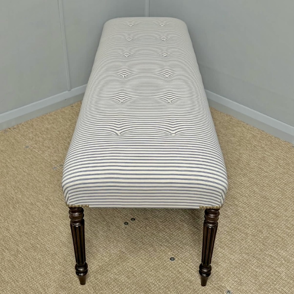 A pair of long upholstered benches featuring grey and white striped ticking fabric with deep button tufting set upon dark turned and fluted timber legs. View VII