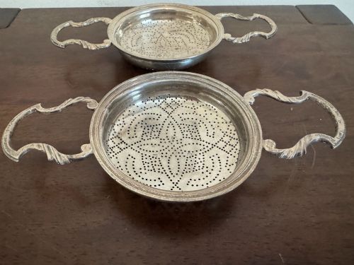 fig 1. A matched pair of George III sterling silver lemon strainers featuring pierced geometric bowl patterns and dual side handles.