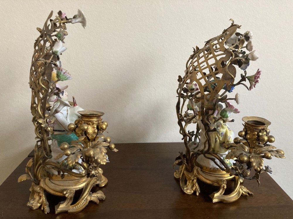 A pair of 18th-century Rococo gilt bronze candelabra featuring seated Meissen porcelain musician figures against floral trellis backdrops. View V