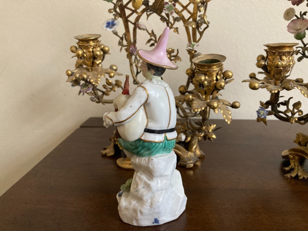 A pair of 18th-century Rococo gilt bronze candelabra featuring seated Meissen porcelain musician figures against floral trellis backdrops. View X