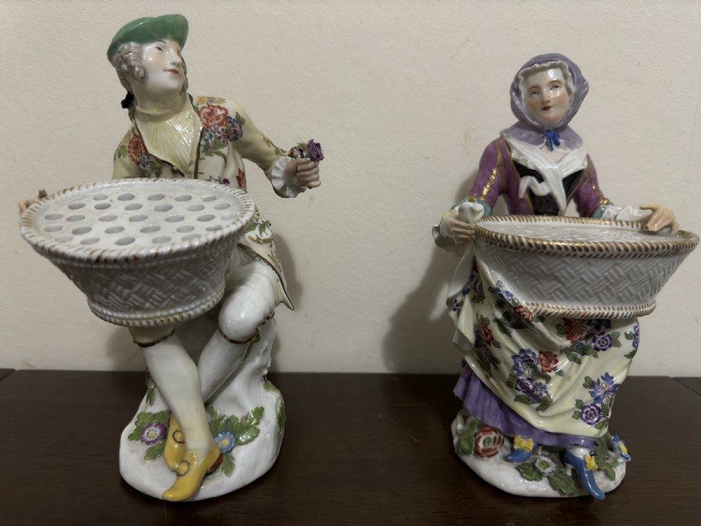 A pair of 18th-century Meissen hard-paste porcelain figures of a seated man and woman holding lattice-patterned basket flower holders with pierced tops. View X