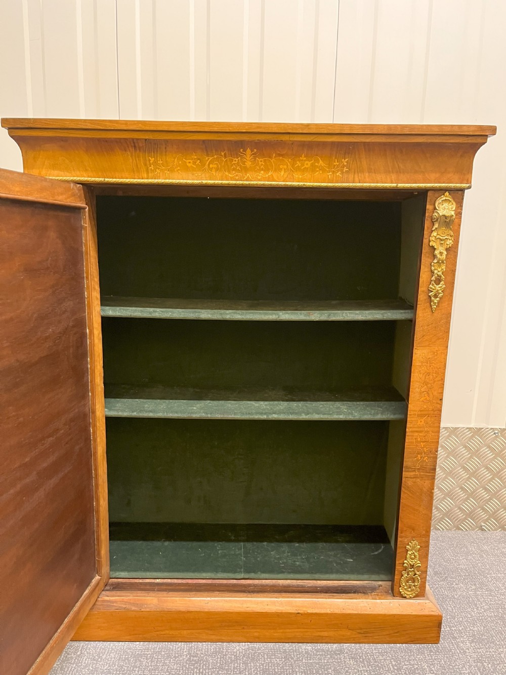 A Regency rosewood side cabinet featuring a brass lattice door with pleated fabric backing, ornate brass mounts, and brass marquetry inlays. View II