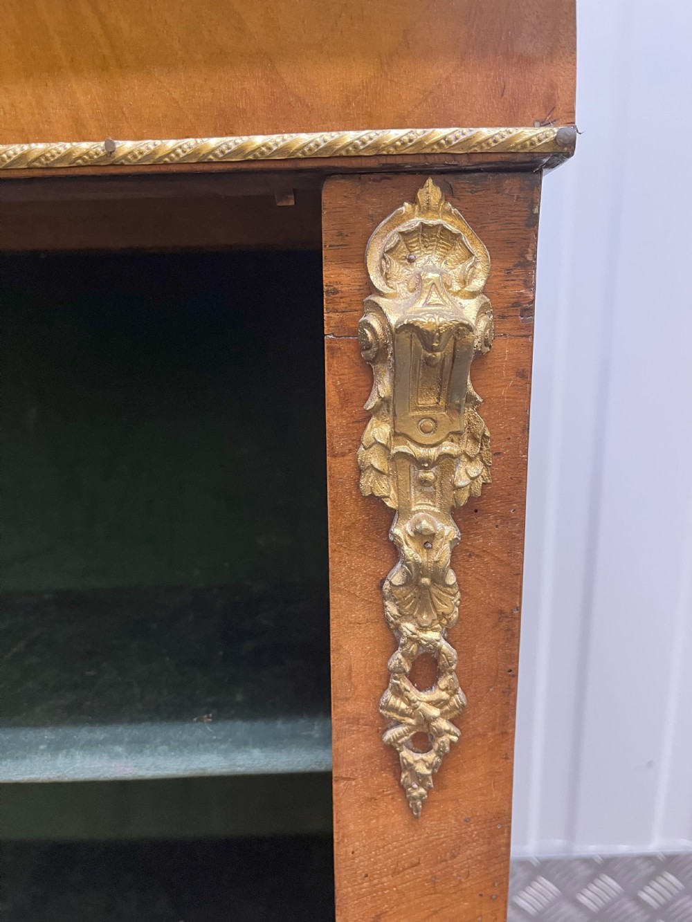 A Regency rosewood side cabinet featuring a brass lattice door with pleated fabric backing, ornate brass mounts, and brass marquetry inlays. View III