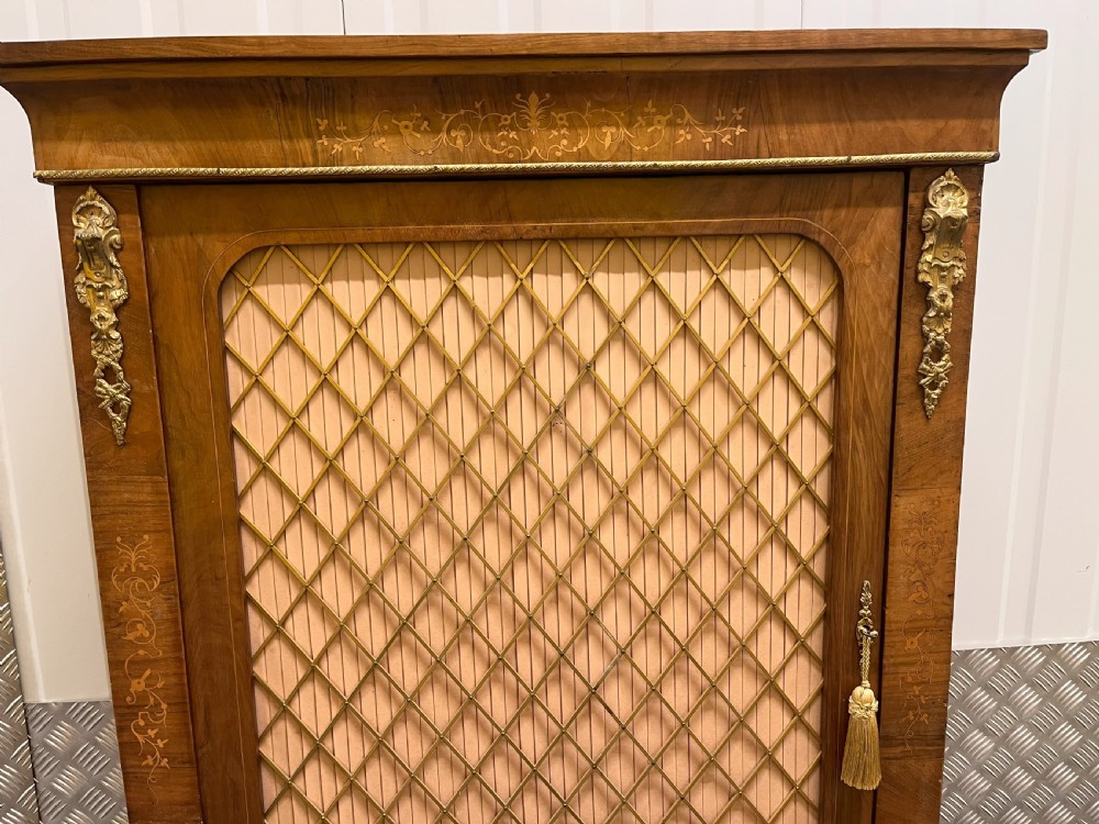 A Regency rosewood side cabinet featuring a brass lattice door with pleated fabric backing, ornate brass mounts, and brass marquetry inlays. View X