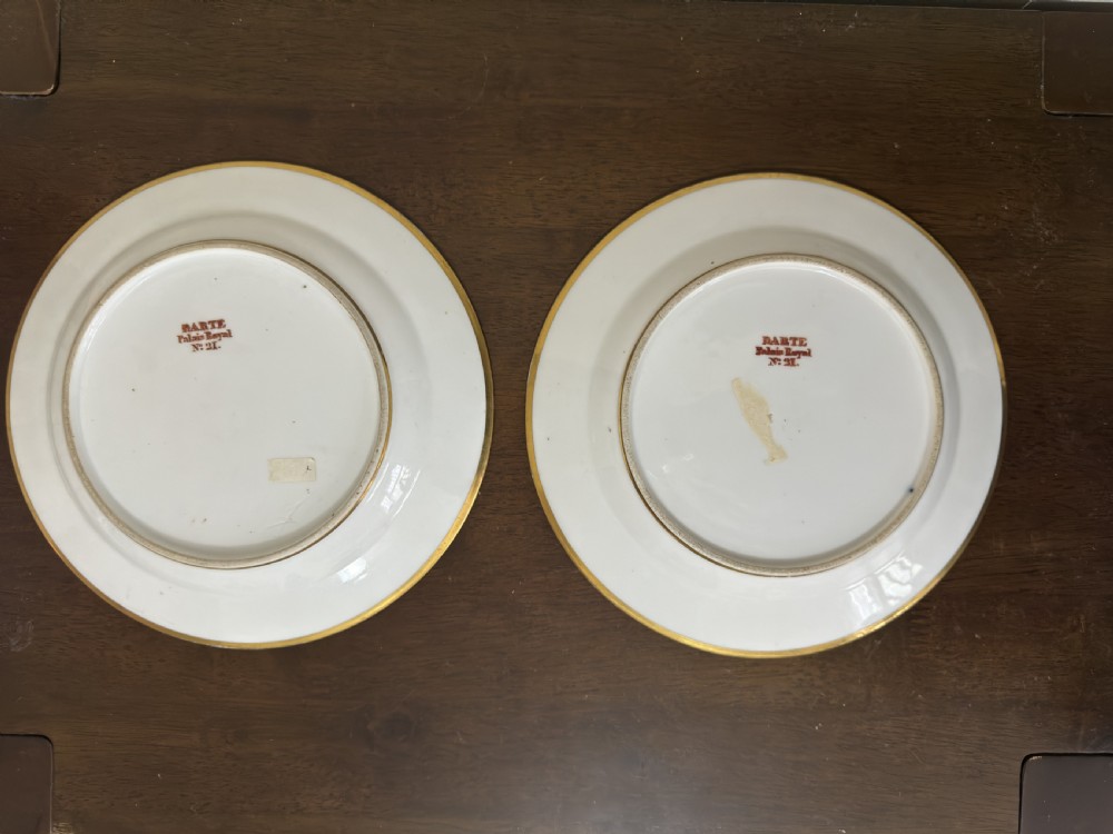 A pair of circular French Empire porcelain cabinet plates featuring hand-painted pastoral scenes surrounded by heavy gilded borders on cobalt blue. View II
