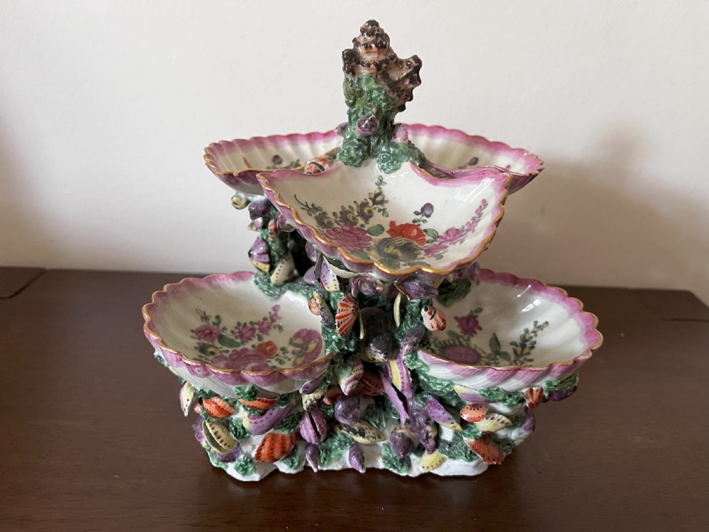 A multi-tiered 18th-century porcelain sweetmeat stand composed of shell-shaped dishes supported by a column encrusted with miniature shells and painted with floral motifs. View V