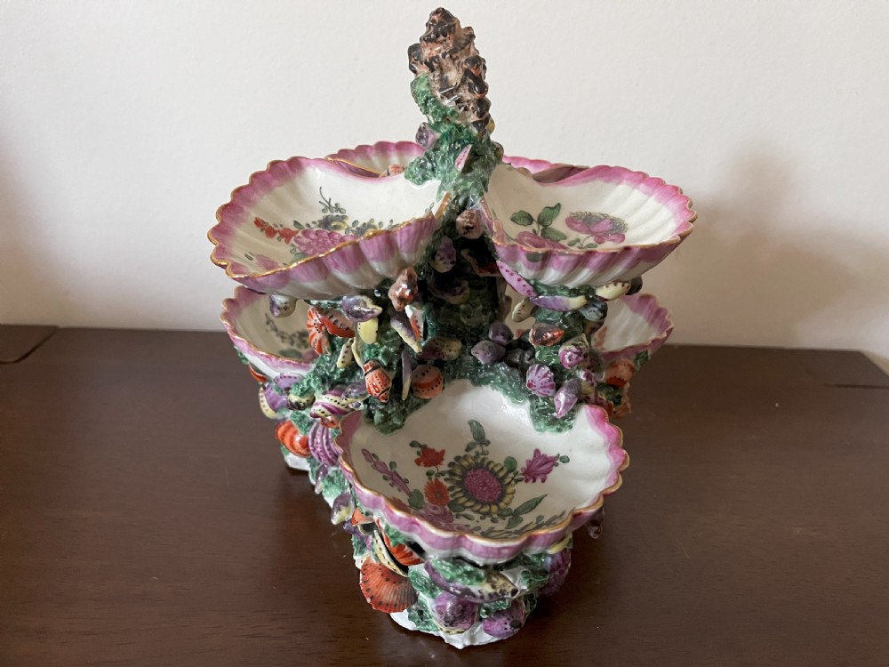 A multi-tiered 18th-century porcelain sweetmeat stand composed of shell-shaped dishes supported by a column encrusted with miniature shells and painted with floral motifs. View VI