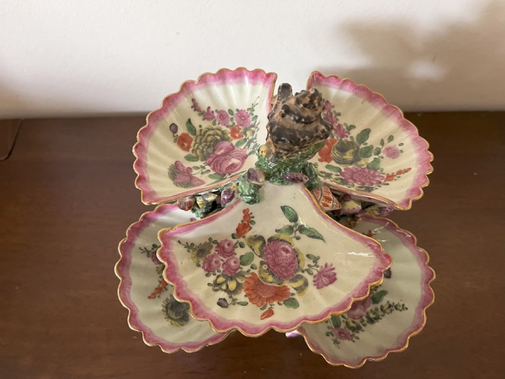 A multi-tiered 18th-century porcelain sweetmeat stand composed of shell-shaped dishes supported by a column encrusted with miniature shells and painted with floral motifs. View VII