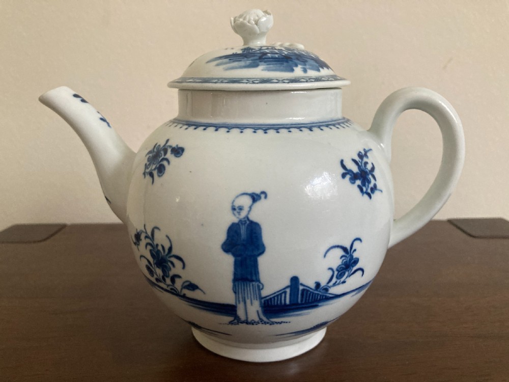 An 18th-century First Period Worcester blue and white soft-paste porcelain teapot featuring a painted chinoiserie figure, domed lid, and floral knop.