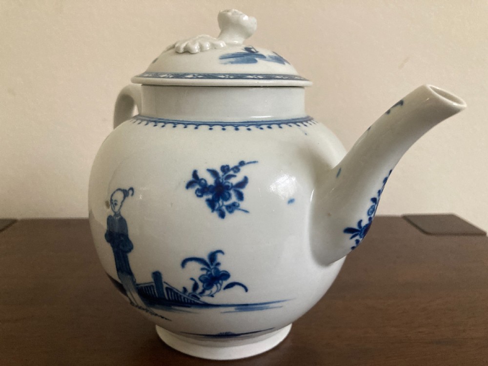 An 18th-century First Period Worcester blue and white soft-paste porcelain teapot featuring a painted chinoiserie figure, domed lid, and floral knop. View V