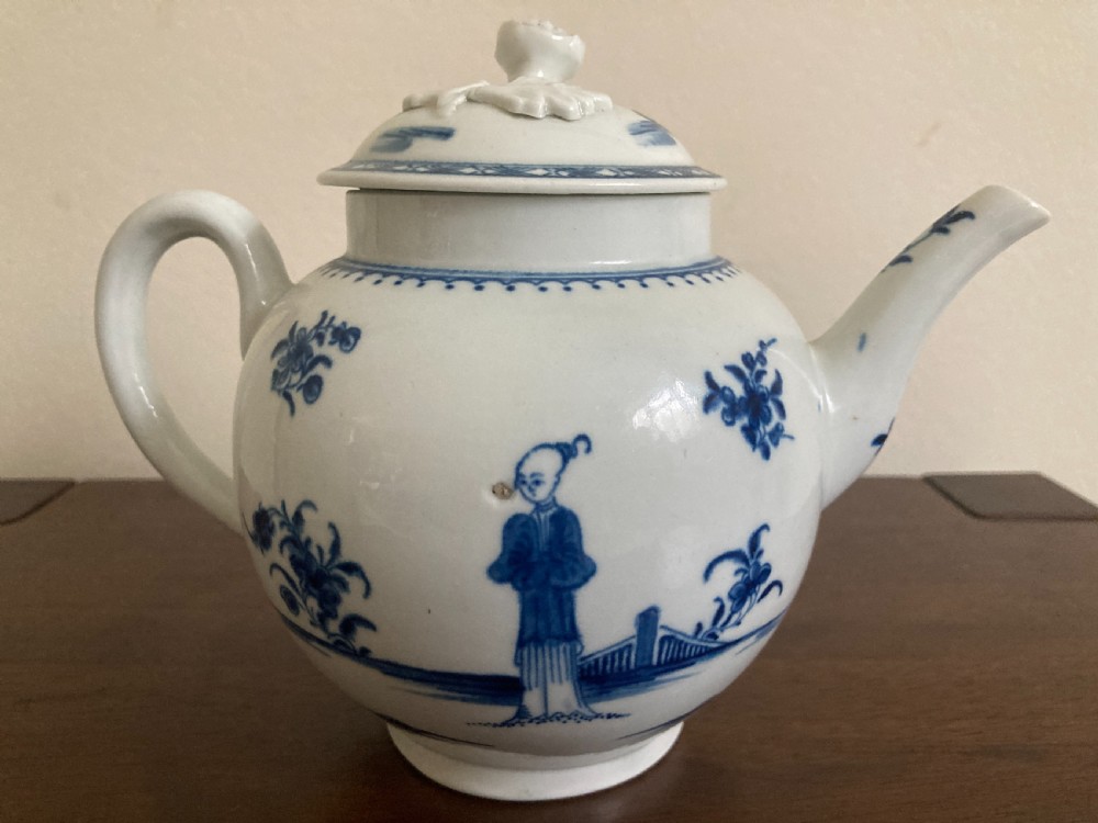An 18th-century First Period Worcester blue and white soft-paste porcelain teapot featuring a painted chinoiserie figure, domed lid, and floral knop. View VI