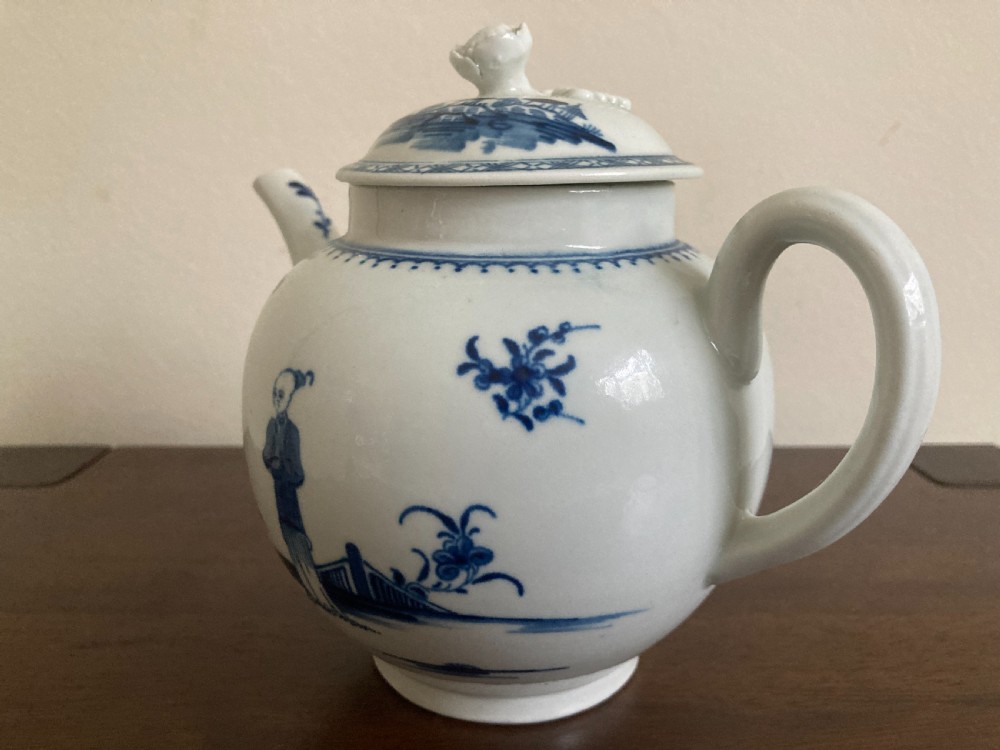 An 18th-century First Period Worcester blue and white soft-paste porcelain teapot featuring a painted chinoiserie figure, domed lid, and floral knop. View IX