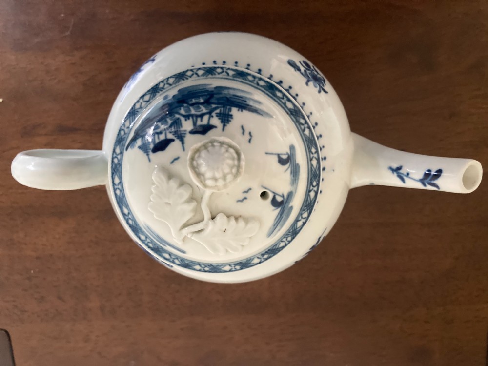 An 18th-century First Period Worcester blue and white soft-paste porcelain teapot featuring a painted chinoiserie figure, domed lid, and floral knop. View XI