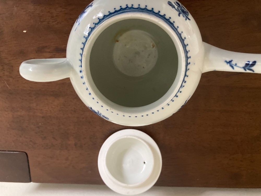 An 18th-century First Period Worcester blue and white soft-paste porcelain teapot featuring a painted chinoiserie figure, domed lid, and floral knop. View XII