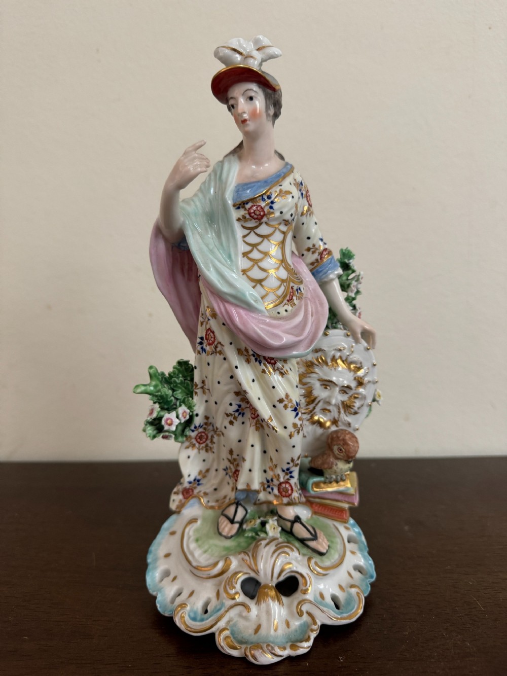An eighteenth-century Derby porcelain figurine representing Minerva, styled with hand-painted polychrome enamels, gilding, an owl, and a shield on a pierced base.