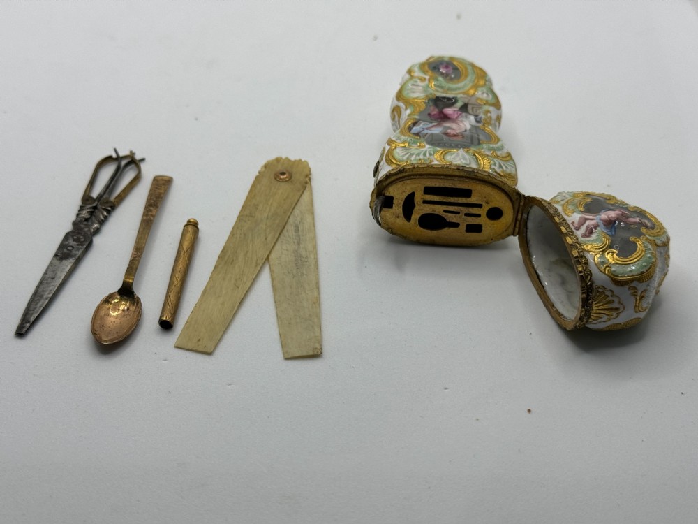 An antique South Staffordshire enamel etui case featuring hand-painted figurative panels framed by raised gilt scrollwork on a white background. View IX