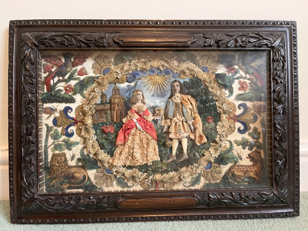 A 17th-century stumpwork embroidery picture depicting King Charles II and a lady in silk and metallic thread relief, set within a dark carved wooden frame.