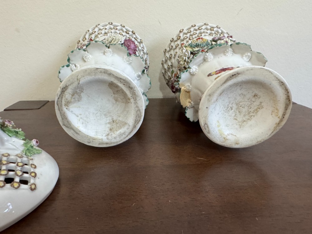 A pair of 18th-century soft-paste Derby porcelain frill vases featuring reticulated rims, hand-modelled floral encrustations, female mask appliques, painted insects, and lid finials shaped as birds. View XVI