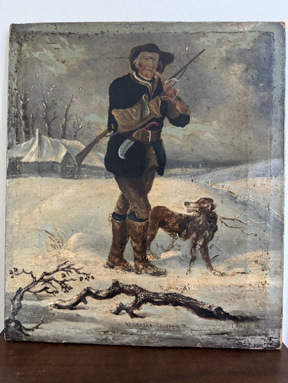 A 19th-century oil painting depicting a winter trapper standing in the snow with a rifle and a dog, signed T. Hicks 1854.