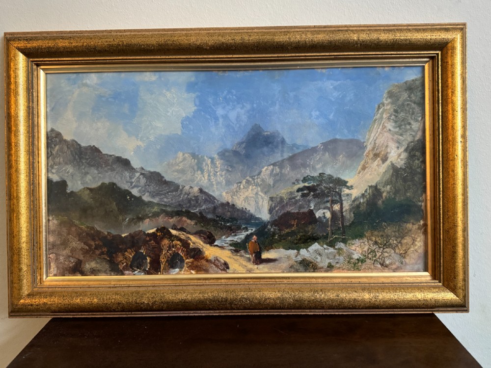 A 19th-century oil painting depicting a rocky mountain landscape with a winding stream and figures, enclosed in a gilded wooden frame.