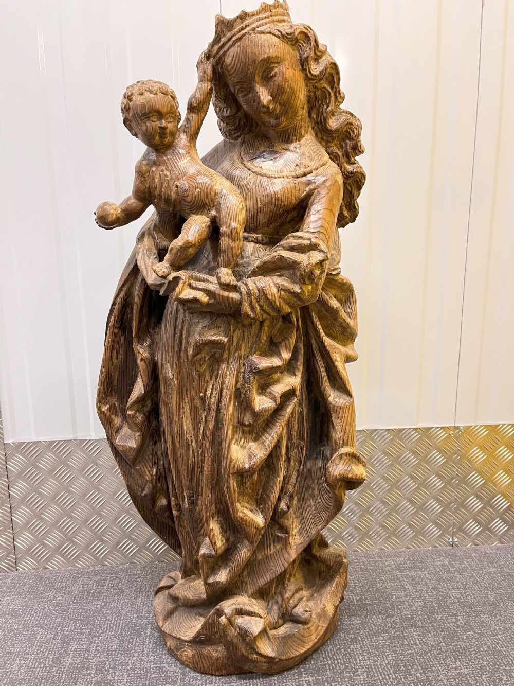 A 19th-century hand-carved wooden statue depicting the crowned Virgin Mary holding the Christ child in detailed draped robes.