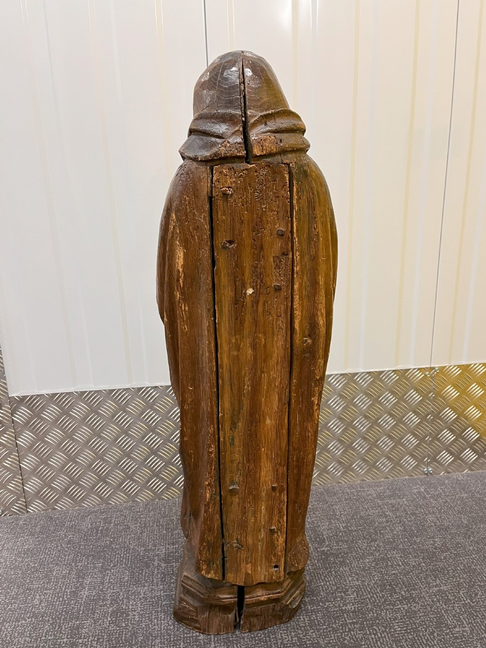 Carved dark oak sculpture depicting a hooded woman in draped robes with hands crossed over her chest, standing on an octagonal wooden base. View IV