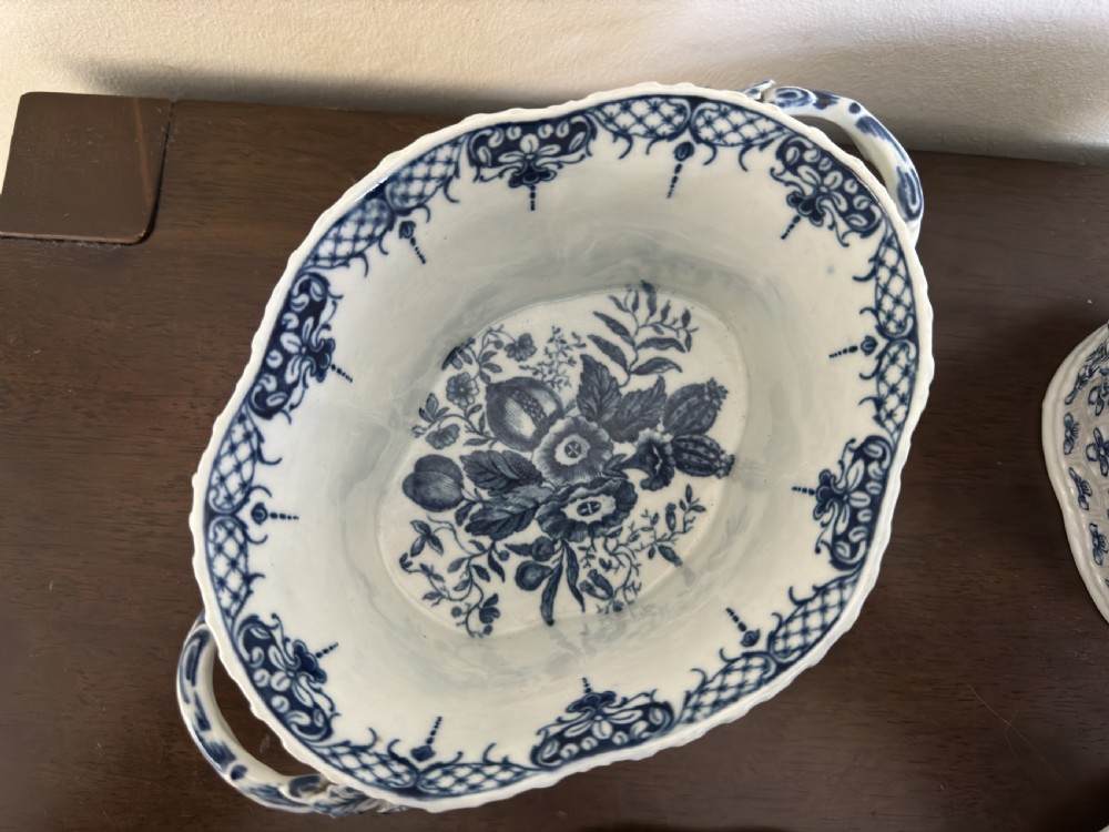 A pair of 18th-century Worcester blue and white porcelain chestnut baskets with reticulated covers, twig handles, and encrusted floral decorations. View VI