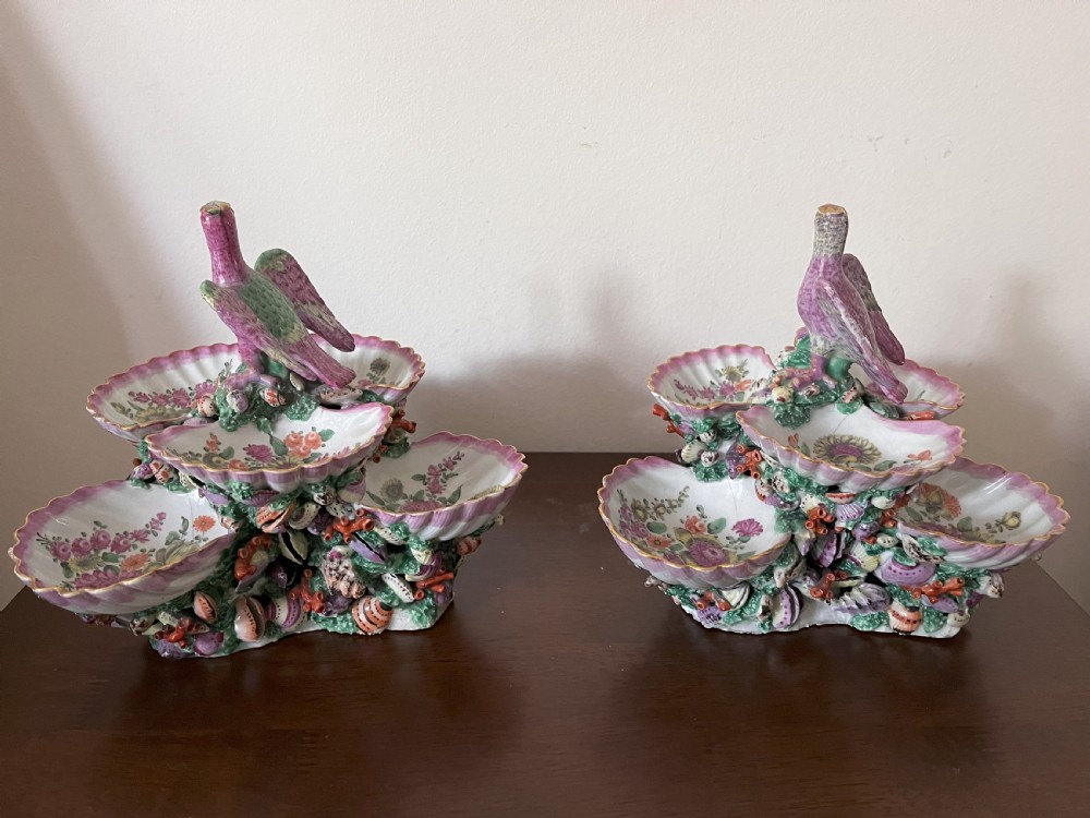 A pair of 18th-century First Period Worcester soft-paste porcelain tiered centrepieces featuring moulded shell dishes, encrusted marine decoration, and bird finials in pink and green enamels. View V