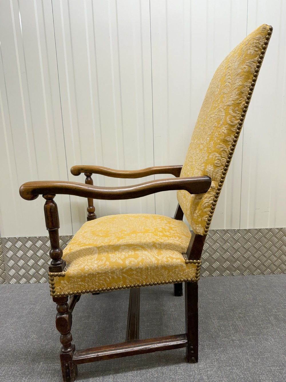 An antique Charles II style walnut elbow chair featuring turned wood legs, scrolled armrests, brass stud details, and yellow damask upholstery. View II