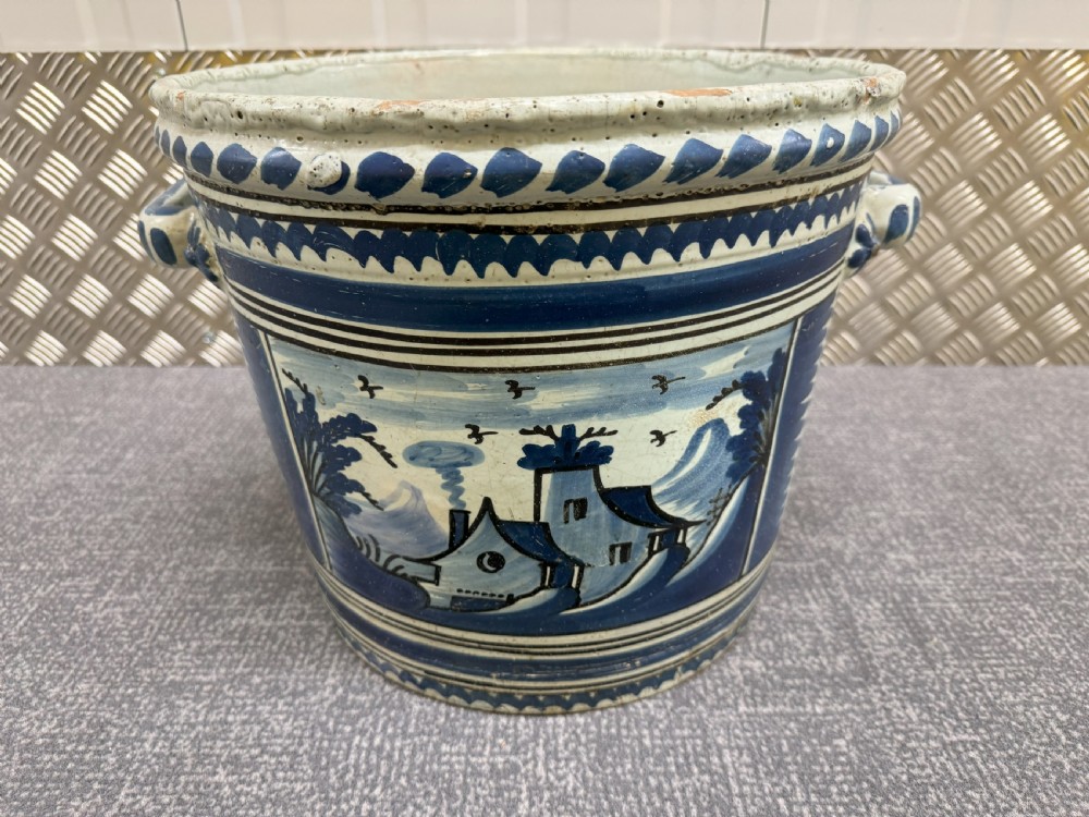 An 18th-century French Nevers faience ceramic orange pot decorated with hand-painted cobalt blue landscape motifs, geometric borders, and twin side handles.