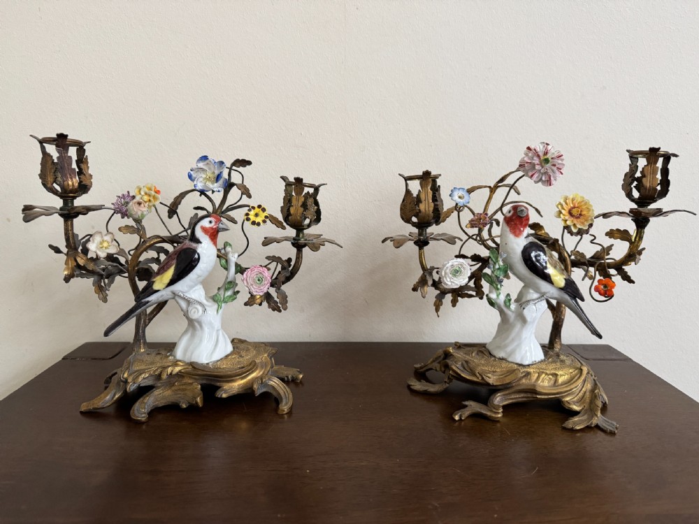 A pair of nineteenth-century French ormolu candelabra featuring hand-painted porcelain birds surrounded by gilt branches and floral mounts.