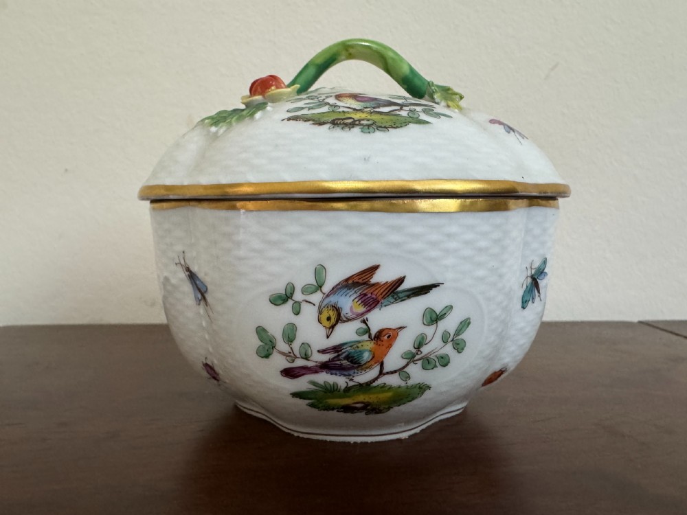 A white Dresden porcelain lidded bowl featuring relief basketweave moulding, hand-painted birds and insects, a branch handle, and gilt borders.