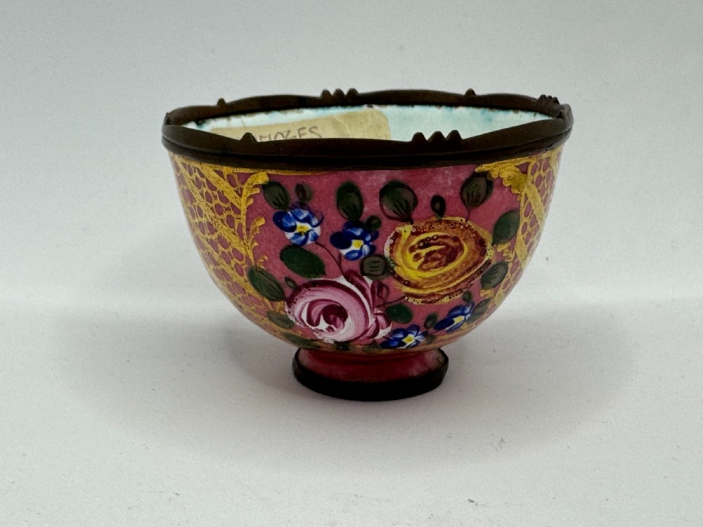 An 18th-century Limoges enamel salt bowl featuring hand-painted floral motifs on a pink ground with gilt lattice detailing and a dark metal rim. View V