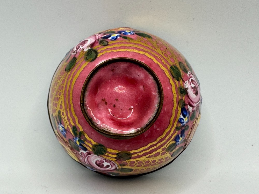 An 18th-century Limoges enamel salt bowl featuring hand-painted floral motifs on a pink ground with gilt lattice detailing and a dark metal rim. View X